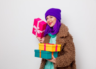Beautiful young girl with purple hair in jacket with holiday gift boxes on white background.