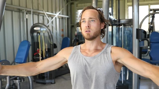 Man at fitness gym. Man doing butterfly chest workout on fitness machine at gym. Athlete working out chest muscles doing strength training exercises on gym chest fly machine equipment. 59.94 FPS