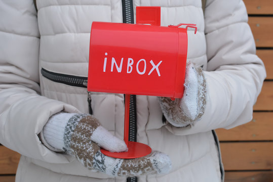 Красный почтовый ящик с надписью "Inbox" в руках у девушки