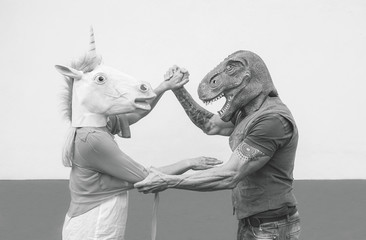 Crazy couple dancing and wearing dinosaur and unicorn mask - Senior trendy people having fun masked...