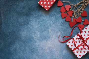 Obraz premium Valentines Day background. Red hearts and gift boxes on blue background. Copy space, top view