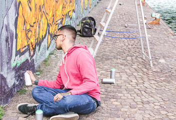 Street artist painting colorful graffiti on a wall under the bridge - Urban man performing with murales - Concept of modern contemporary art