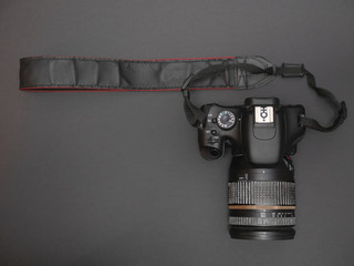view from top on dslr photo video camera with black strap. flat lay low key image