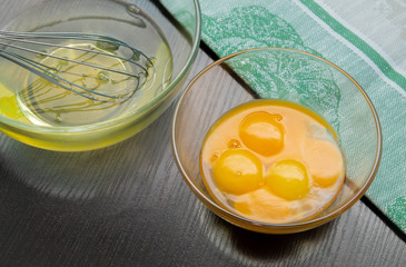 egg whites and yolks in transparent glass cups with a whisk next