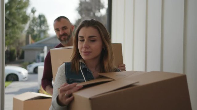 Young family moving into a new home they just bought. Couple brining boxes with stuff  / New start 