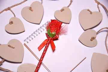 Red rose on  Blank notepad for copy space and Wooden hearts shape  on white blackground . Valentines Day background.  .  wedding day