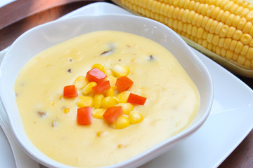 Corn soup and tomato in white bowl on  wooden background.closeup