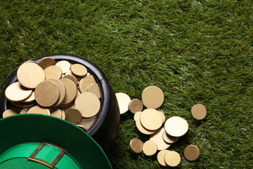 Leprechaun's green hat and black cauldron full of gold on the grass