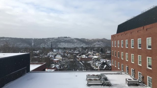 A wintry establishing shot looking out of an office building or hospital with a small valley town in the distance. Pittsburgh suburbs.  	
