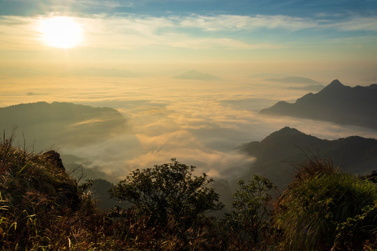 Fototapeta sunrise over mountain and fog with grass foreground at chiang Rai, Thailand