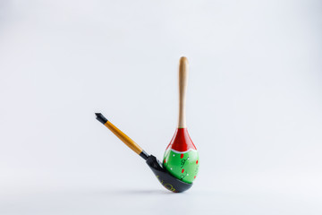 A wooden spoon with a floral ornament in the traditional Russian folk style and a Mexican maracas with a traditional pattern on a white background. To advertise the Russian-Mexican cuisine.