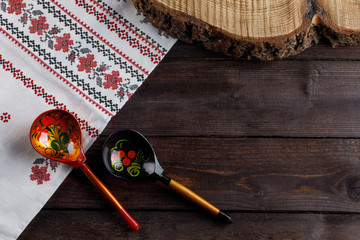 Wooden spoons with floral ornament in traditional folk Russian Khokhloma style on wooden table with a tablecloth with a traditional Russian pattern.