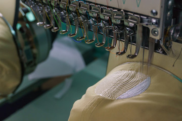 Embroidery machine needle in Textile Industry at Garment Manufacturers, Embroidery cap in progress, Needle with thread (selective focus and soft focus)