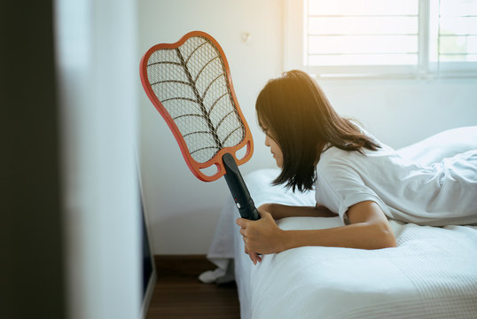 Asian woman using mosquito swatter,Female with mosquito electric net racket