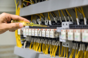 Electricians hands testing current  electric in control panel.