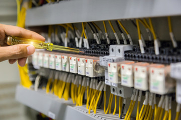 Electricians hands testing current  electric in control panel.