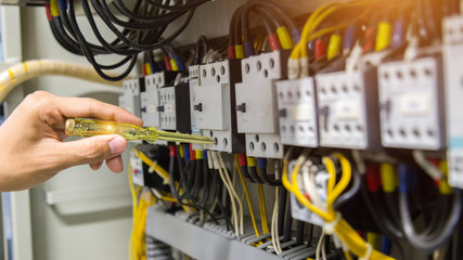 Electricians hands testing current  electric in control panel.