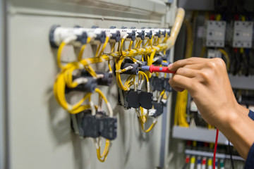 Electricians hands testing current  electric in control panel.