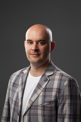 Obraz premium Cute bald man in a jacket and t-shirt shows against a gray wall