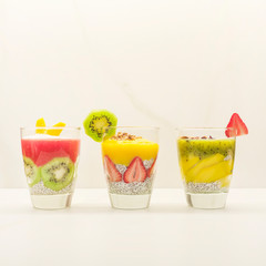 Healthy vanilla chia pudding in a glass with fresh fruits. Vegan chia pudding with almond milk in a glass. Healthy breakfast. Chia with kiwi and mango, strawberry in glass on white background.