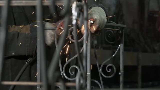 Close-up Is A Blacksmith In Protective Clothing Welding Elements