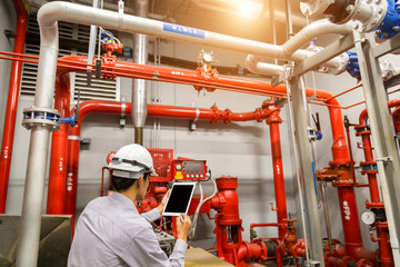 Engineer with tablet check red generator pump for water sprinkler piping and fire alarm control...