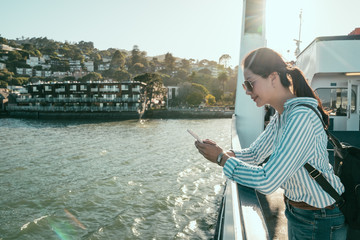 tourist holding cellphone standing on boat