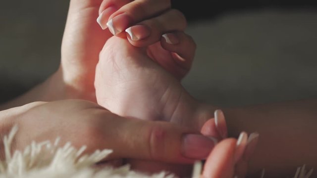 Little baby feet in hands of mother, close up.