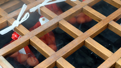 Onsen eggs placed in small nets hanging from a wood panel to be steamed by thermal heat from the hot spring.