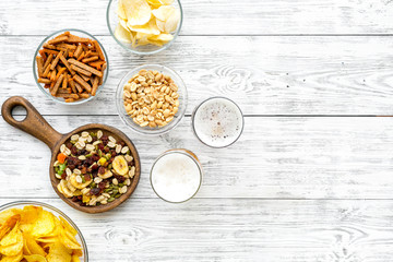 Snacks and beer. Chips, nuts, rusks near beer on white wooden background top view copy space