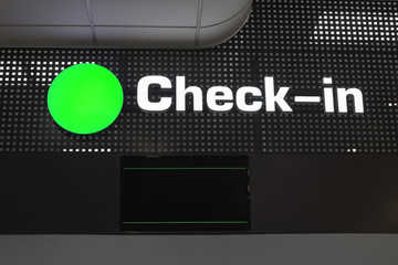 Check in desk at international airport, checkin counter and monitor for flight information display, green round sign close up, layout for passenger air transportation and flight ticket registration