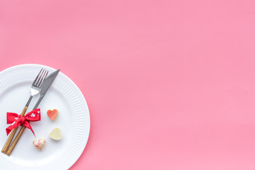 Dating on Valentine's day concept. Festive dishes, tableware on plate on pink background top view copy space