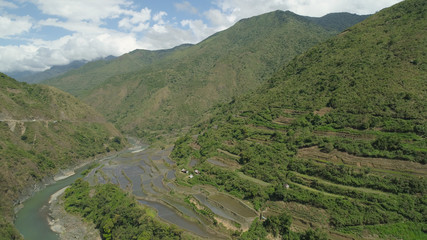 Aerial view of rice terraces and agricultural land on the slopes of the mountains. Mountains covered forest, trees. Cordillera region. Luzon, Philippines.