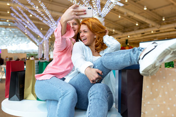 Obraz na płótnie Canvas Two happy friends is taking selfie while shopping in mall.