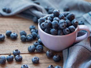 Bluelerry in ceramic bowl on wood floor.