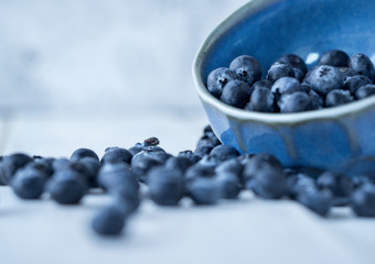 Bluelerry in ceramic bowl on wood floor.