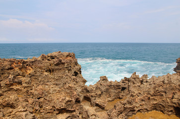 Fototapeta na wymiar Natural rock formation with the wave at Timang Beach in sunny day, Yogyakarta, Indonesia