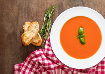 Vegetarian autumn Tomato soup with bread on wooden table, flat lay. Copy space