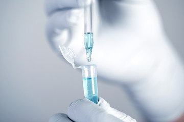 Close up a scientist working in laboratory to analyze blue extracted of a  DNA  molecules in micro...
