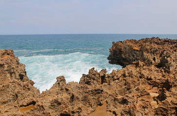 Fototapeta na wymiar Natural rock formation with the wave at Timang Beach in sunny day, Yogyakarta, Indonesia