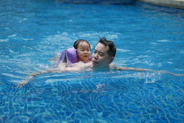 Asian chinese father and daughter having fun in swimming pool