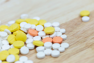 Fototapeta na wymiar Colorful medicine pills tablets or drugs closeup on wood table background.