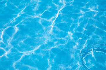 Blue ripped water in swimming pool with sunny reflections for background design.