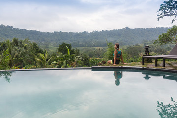 Obraz premium sexy woman enjoying the sun at infinity summer swimming pool at luxurious resort