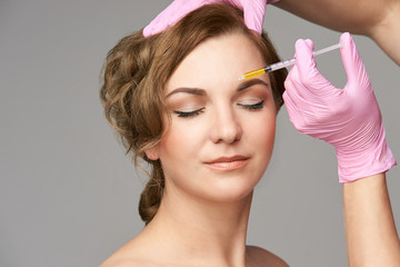 Face needle injection. Young woman cosmetology procedure. Doctor gloves. Brow