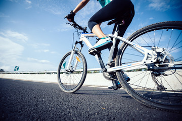 Woman cyclist legs riding Mountain Bike on highway