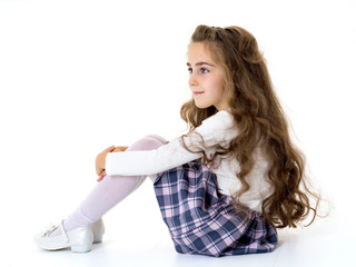 Little girl is sitting on the floor.