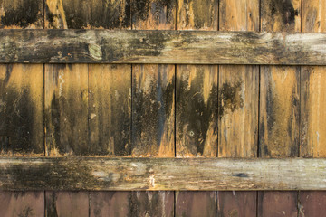 Old yellow gray wooden fence with black spots of mold and dirt. vertical and horizontal lines. rough surface texture