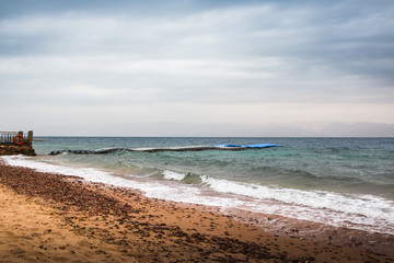 Beach, sea and pier in the water on a cloudy summer day