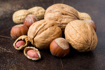 Bunch of nuts in shell and peeled on dark background. Walnuts, hazelnuts and peanuts. Tasty healthy snack, food
